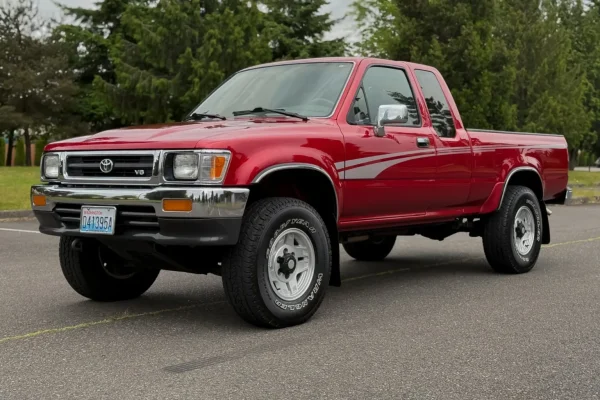 This 1994 Toyota Pickup SR5 XtraCab was initially delivered to Heartland Toyota in Bremerton, Washington, and it shows 125k miles following registration history in the state under the care of a single family. Finished in Garnet Pearl over gray cloth upholstery, the truck is powered by a 3.0-liter V6 linked to a five-speed manual transmission and a dual-range transfer case. Equipment includes 15″ styled alloy wheels, power-assisted front disc brakes, a sunroof, a sliding rear window, a bedliner, air conditioning, cruise control, power windows, and a cassette stereo. Acquired by the selling dealer in 2025, this Toyota pickup is offered at no reserve with a window sticker, manufacturer’s literature, a clean Carfax report, and a clean Washington title. No Reserve: 1994 Toyota Pickup XtraCab SR5 V6 4×4 5-Speed The truck is finished in Garnet Pearl and features a sunroof, a sliding rear window, a bedliner, and halogen headlights. Close-up photographs of the exterior finish and trim are shown in the gallery below. No Reserve: 1994 Toyota Pickup XtraCab SR5 V6 4×4 5-Speed The 15″ styled alloy wheels are mounted with 31×10.50″ Goodyear Wrangler tires. Braking is handled by power-assisted front discs and rear drums with ABS. No Reserve: 1994 Toyota Pickup XtraCab SR5 V6 4×4 5-Speed The cabin features front captain’s chairs and rear seats trimmed in gray cloth, and amenities include air conditioning, cruise control, power windows, power locks, and a cassette stereo with an in-dash CD changer. There is wear on the shift knob and a tear on the driver’s armrest. No Reserve: 1994 Toyota Pickup XtraCab SR5 V6 4×4 5-Speed Instrumentation includes a 110-mph speedometer, a tachometer, and auxiliary gauges for oil pressure, coolant temperature, voltage, and fuel level. The six-digit odometer shows 125k miles. No Reserve: 1994 Toyota Pickup XtraCab SR5 V6 4×4 5-Speed The 3.0-liter 3VZ-E V6 features fuel injection for a factory rating of 150 horsepower and 180 lb-ft of torque. The timing belt was said to have been replaced in December 2005 at 80k miles. No Reserve: 1994 Toyota Pickup XtraCab SR5 V6 4×4 5-Speed Power is sent to the rear via a five-speed manual transmission and a dual-range transmission case. No Reserve: 1994 Toyota Pickup XtraCab SR5 V6 4×4 5-Speed